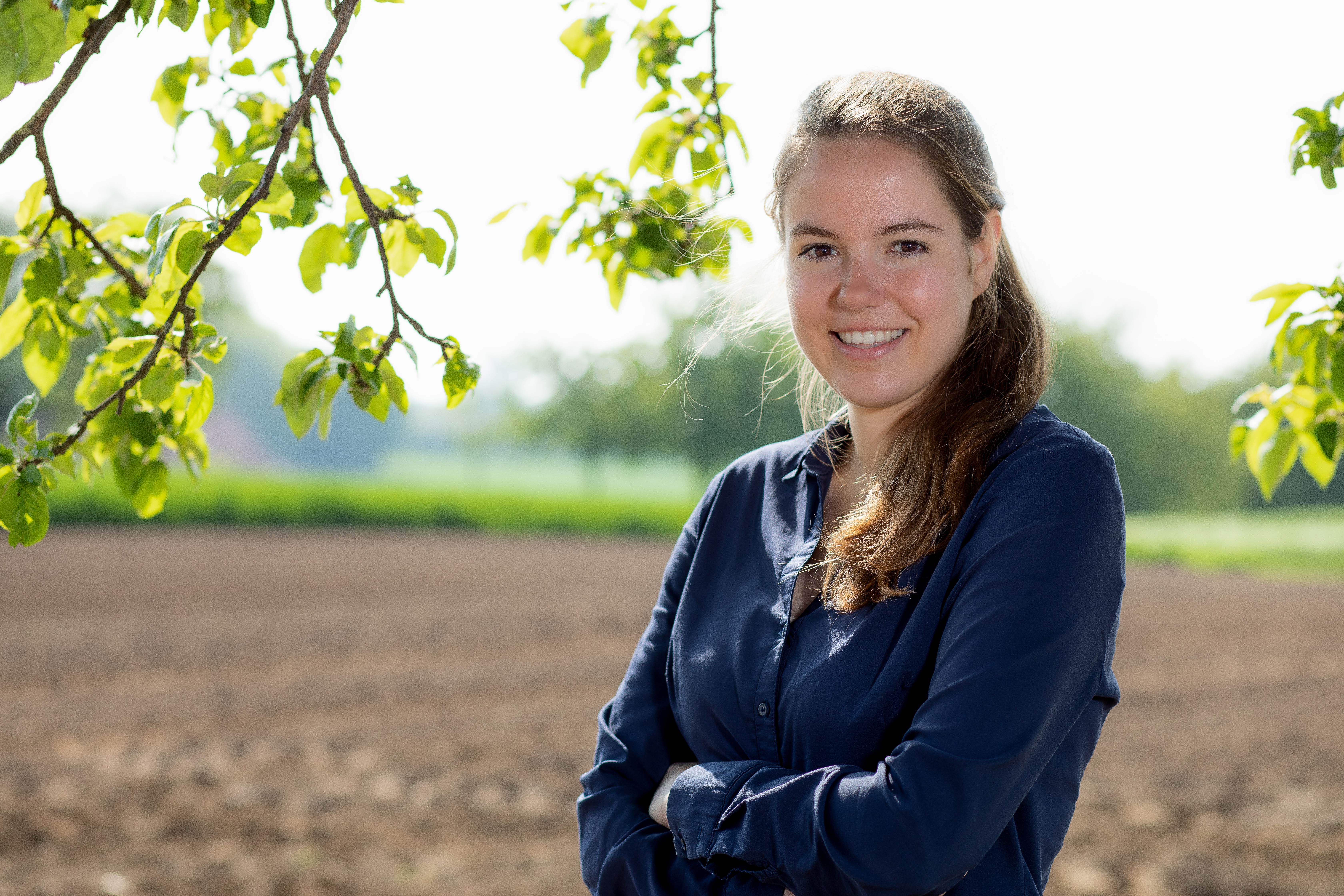 Carolin Schröer von mein DIGITALreferent steht mit verschränkten Armen in der Natur im Schwarzwald und möchte den öffentlichen Dienst in der Personalgewinnung unterstützen